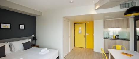 A hotel room with a bed, bedside table, lamp, and two framed pictures on the wall.