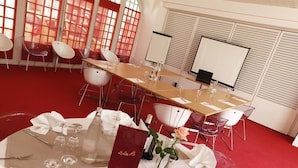 A conference room with a long table, clear chairs, a whiteboard, and a red carpet. - Le Lion D'or (Gémozac)