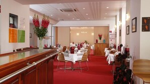 A hotel lobby with a reception desk, multiple dining tables, chairs, and a red carpet. - Le Lion D'or (Gémozac)