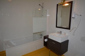 A bathroom with a bathtub, a sink, a mirror, and a hairdryer. - Le Lion D'or (Gémozac)