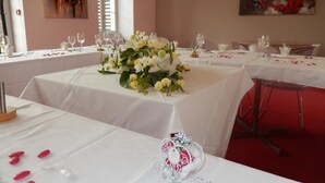 A dining area with tables set for a meal, white tablecloths, and floral centerpieces. - Le Lion D'or (Gémozac)