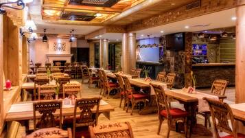 Un restaurant avec des tables et des chaises en bois, une cheminée et un coin bar.