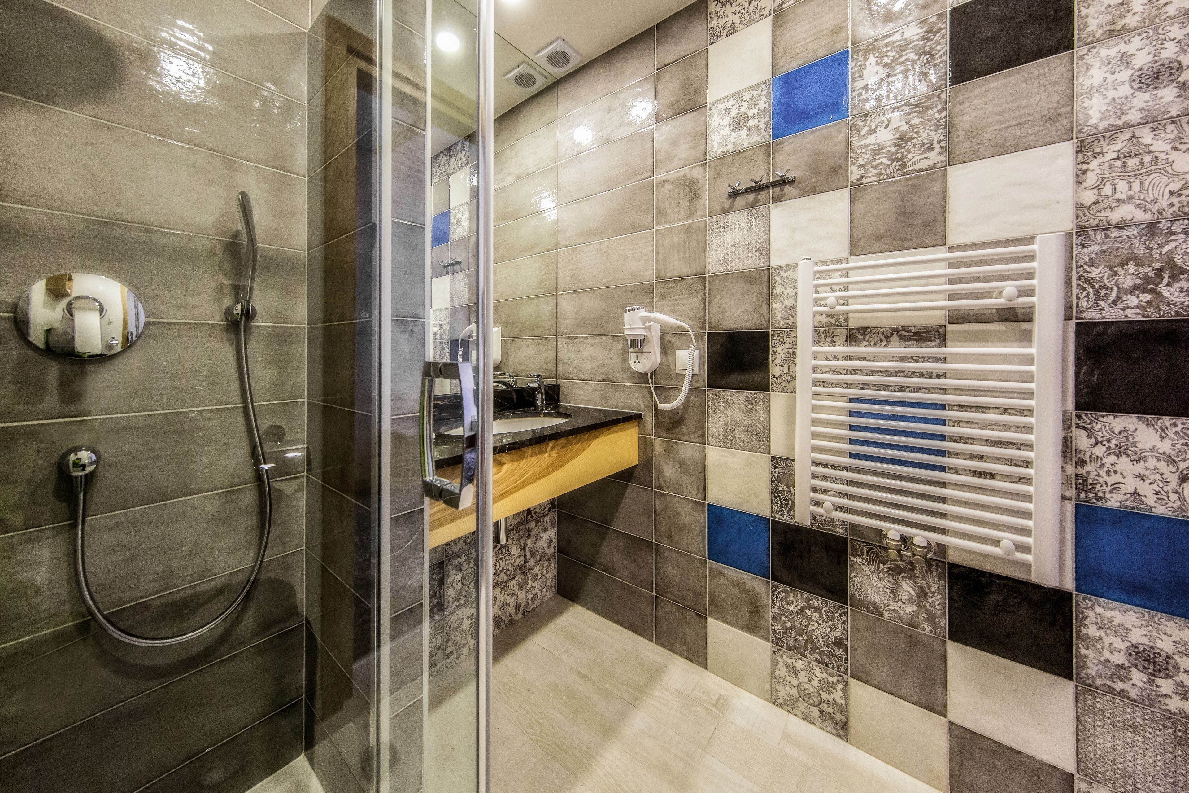 Une salle de bain avec une douche à parois de verre, un porte-serviettes et un lavabo avec un miroir.