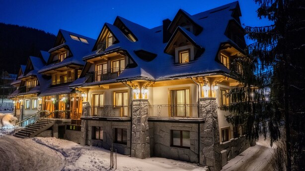 A multi-story lodge with a stone facade, multiple balconies, and a snow-covered landscape. - Gold Hotel (Zakopane)