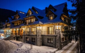 A multi-story lodge with a stone facade, multiple balconies, and a snow-covered landscape. - Gold Hotel (Zakopane)