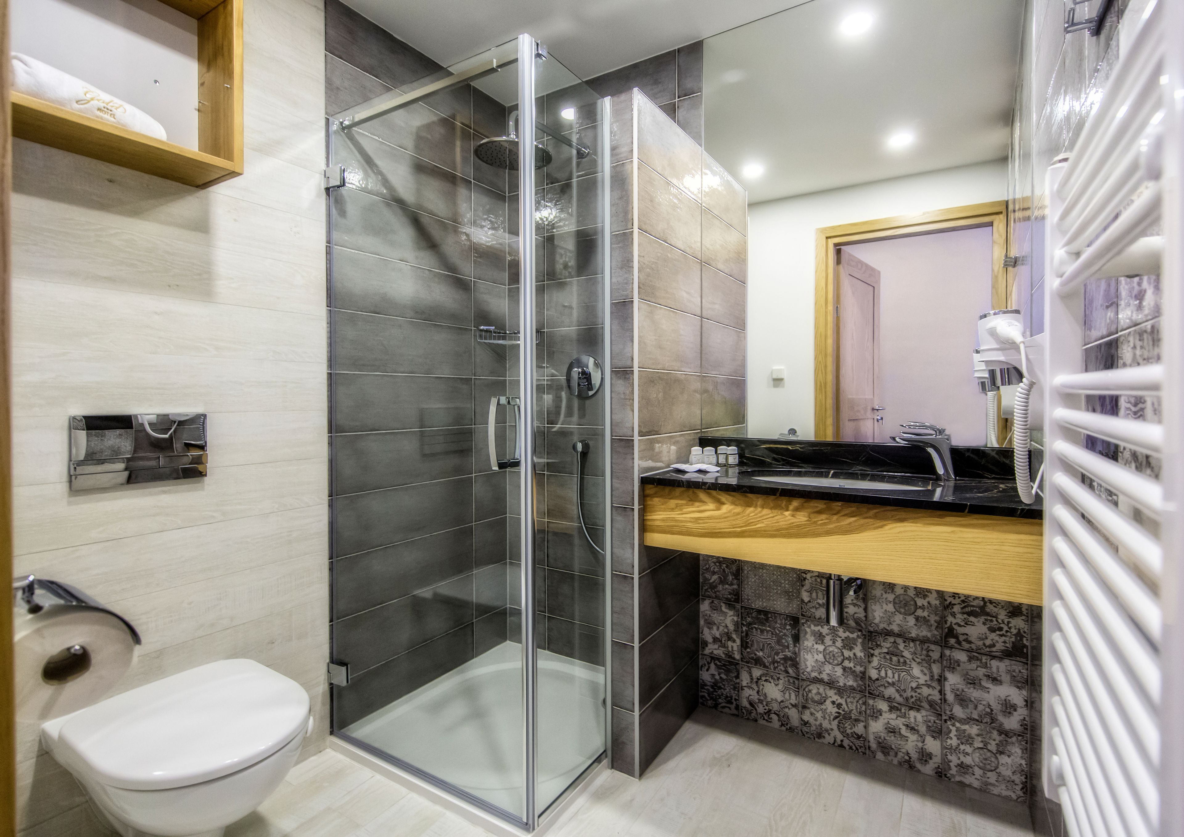 Un baño moderno con ducha de vidrio, inodoro blanco y tocador con encimera de mármol.