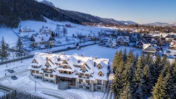A snow-covered village with traditional wooden houses, a ski lift, and a mountain backdrop.