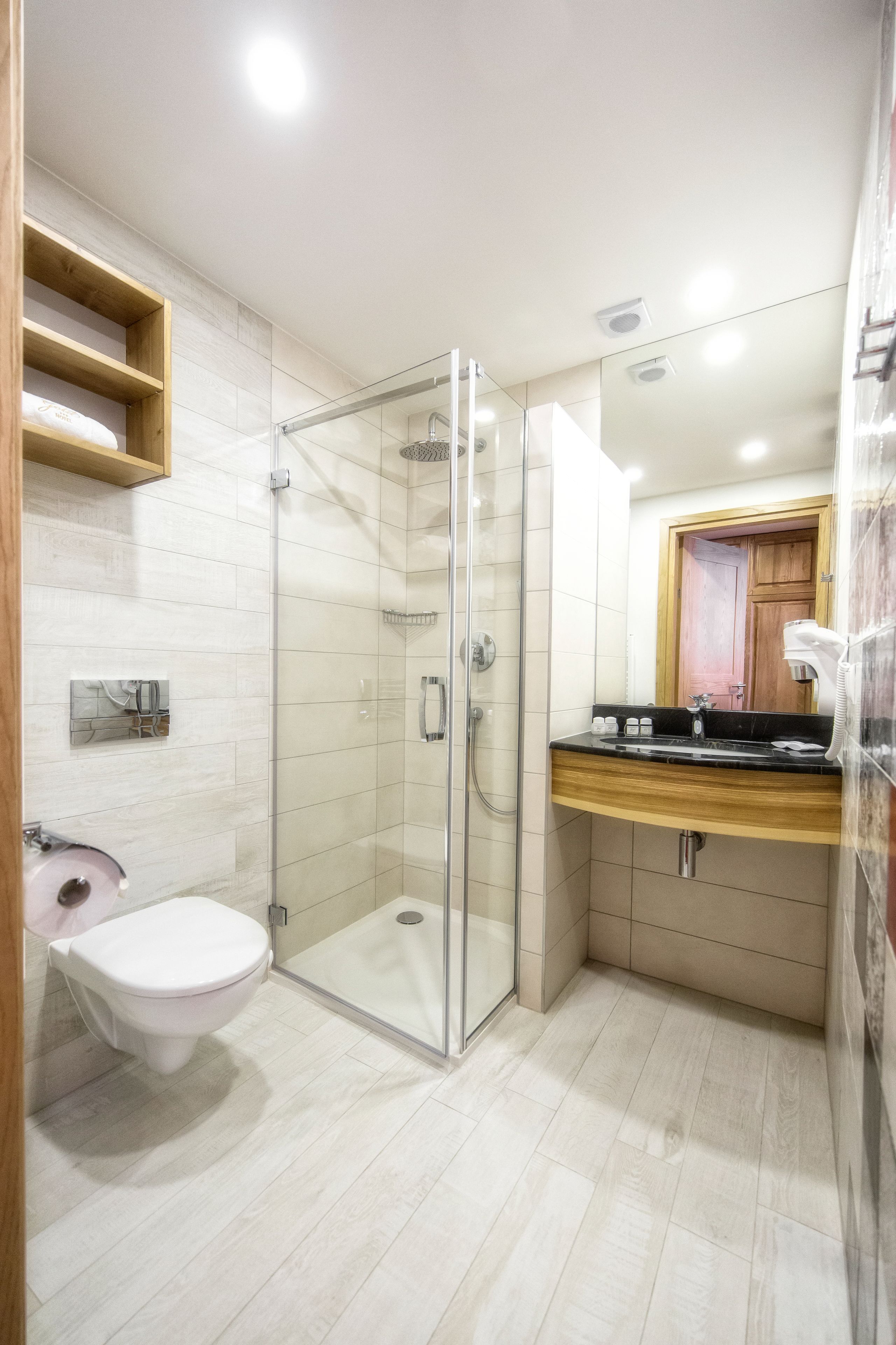 Un baño moderno con cabina de ducha de vidrio, inodoro y tocador con espejo.