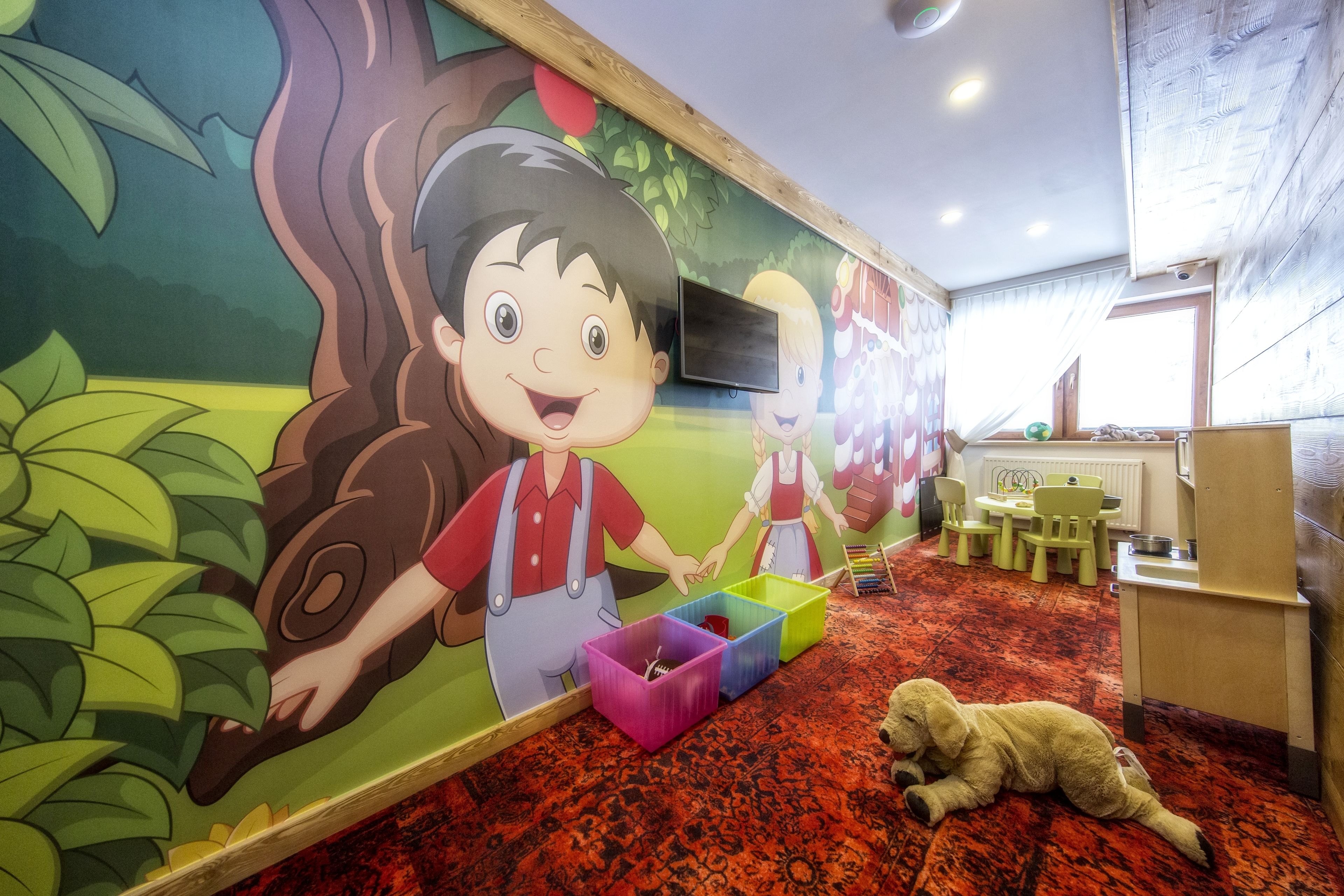 A children's playroom with colorful walls, a red carpet, and a dog lying on the floor.