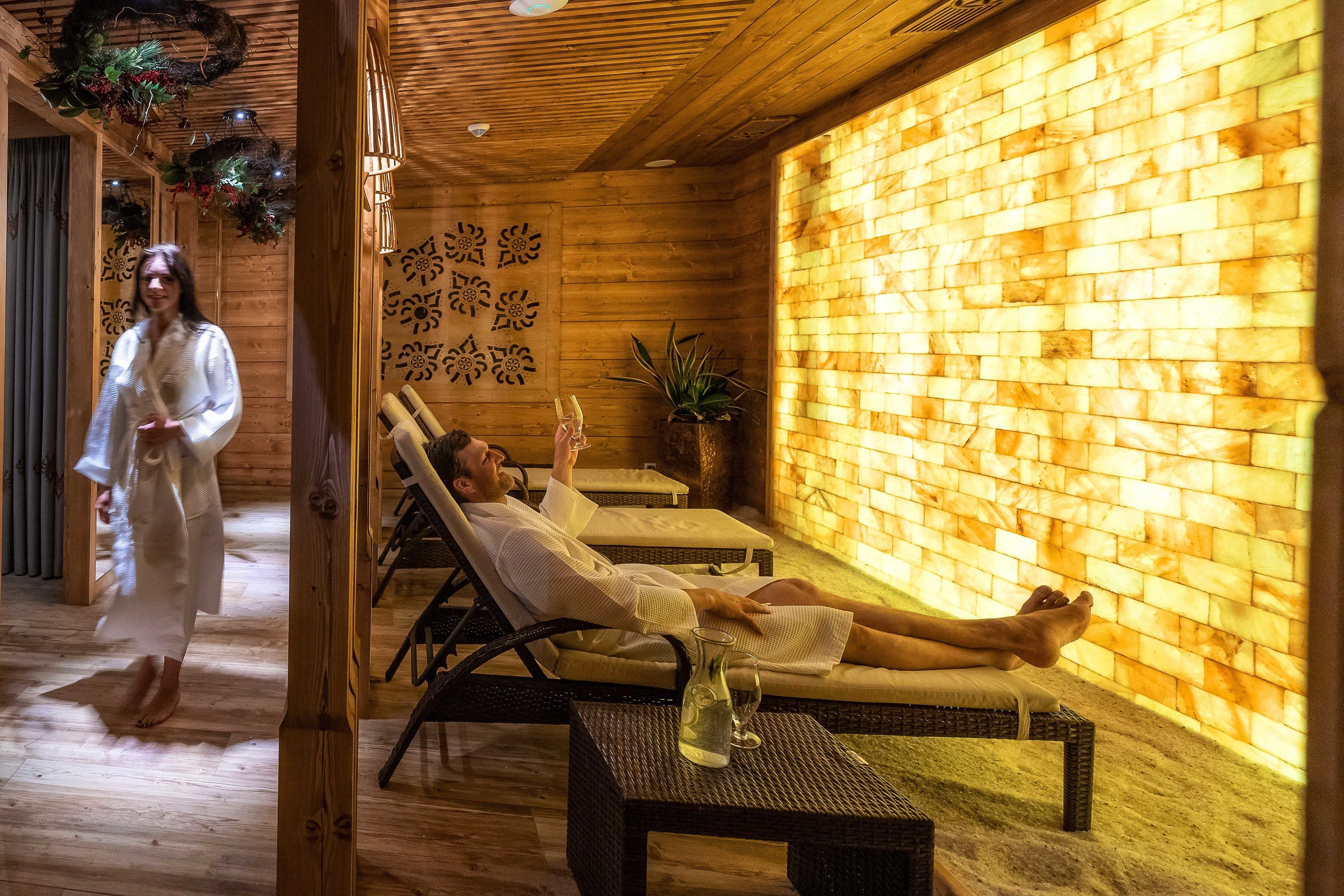 Une salle de spa en bois, dotée de deux fauteuils, d’un mur au motif de briques et d’un panneau décoratif.