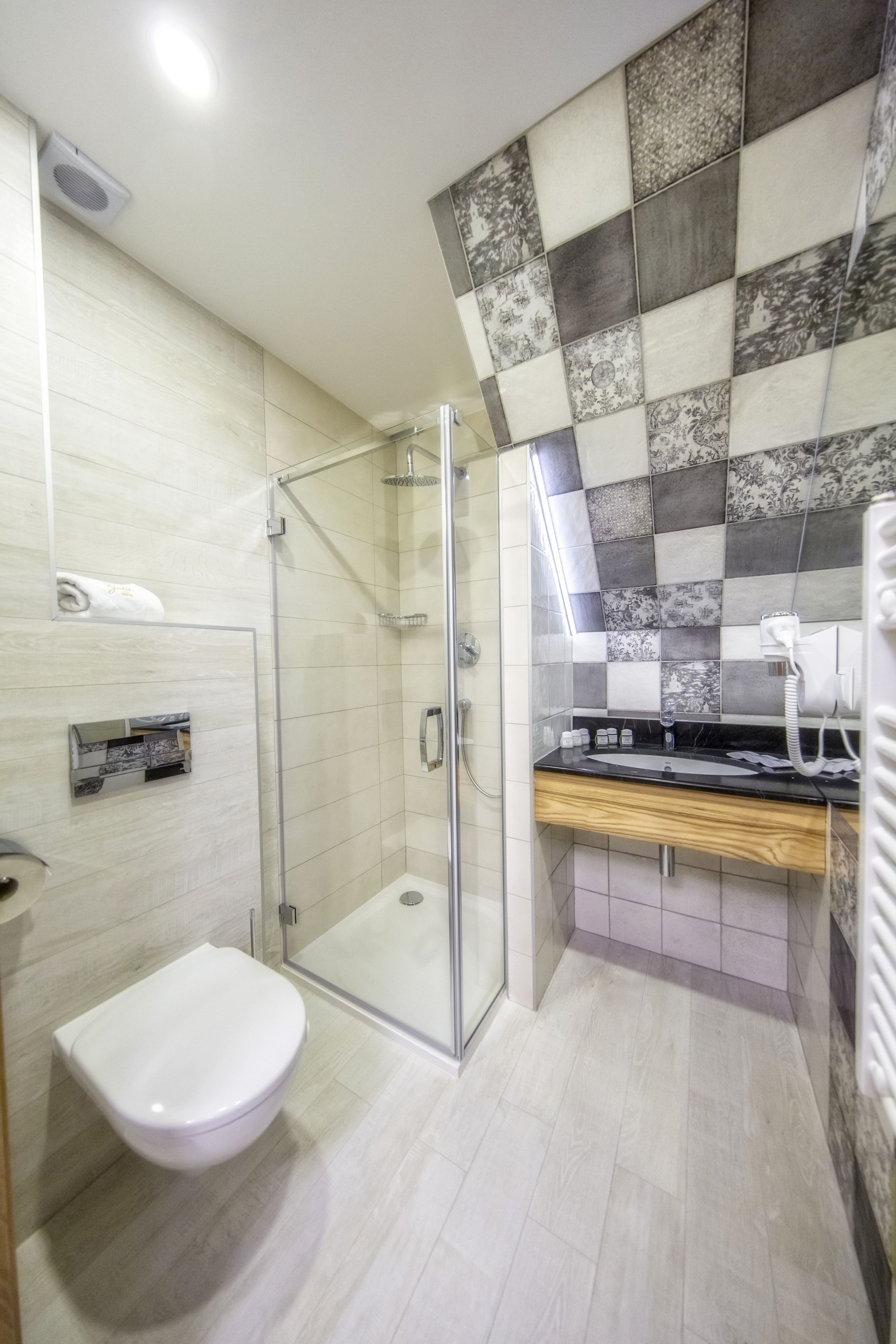 Un baño moderno con cabina de ducha de vidrio, inodoro blanco y tocador con espejo.