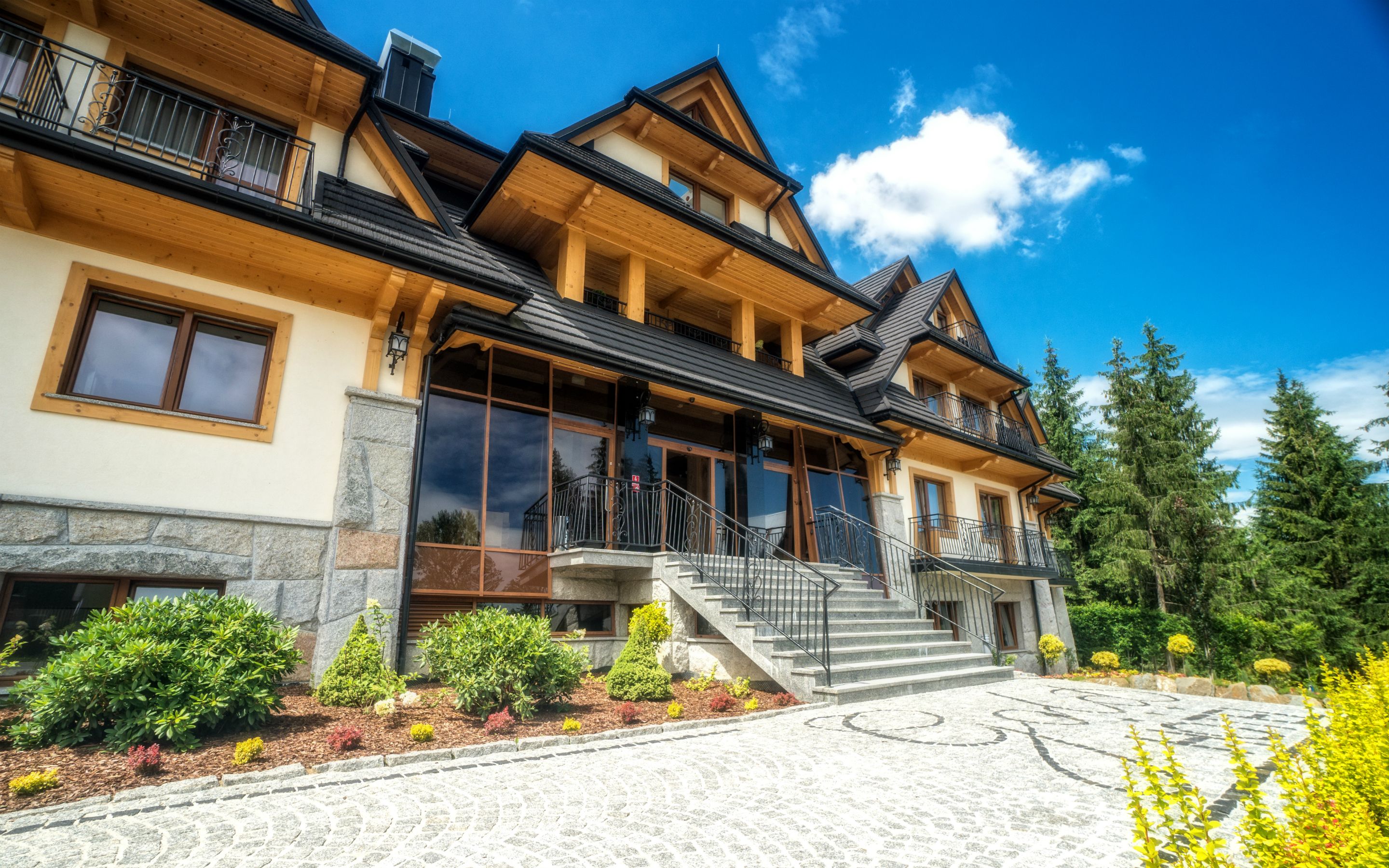 A multi-story chalet with a stone foundation, large windows, and a wooden facade.