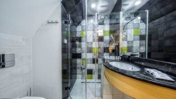 A modern bathroom with a glass-enclosed shower, a sink with a marble countertop, and a mirror.