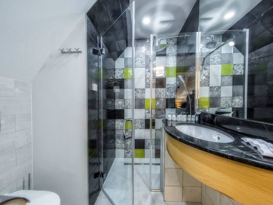 A modern bathroom with a glass-enclosed shower, a sink with a marble countertop, and a mirror.