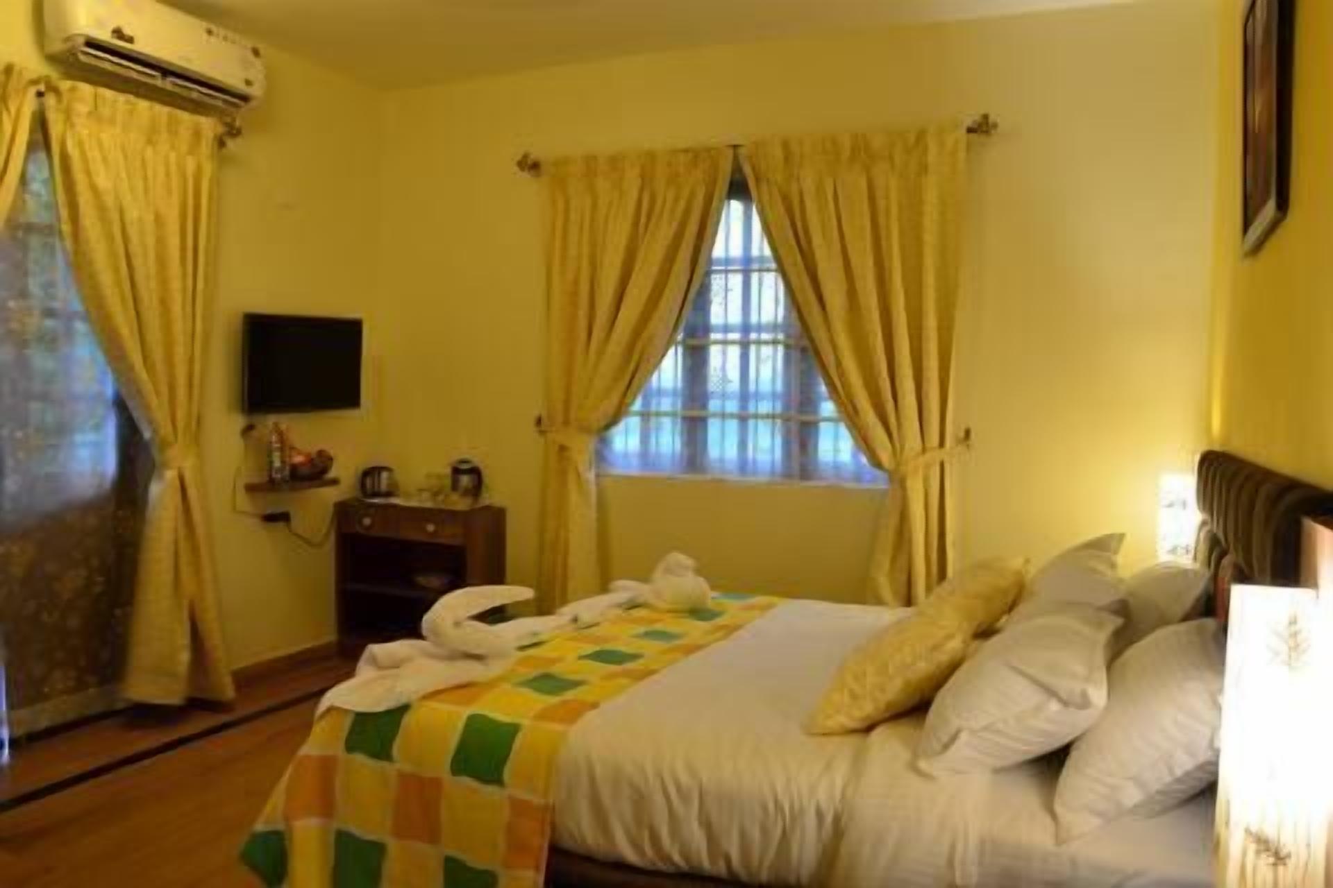 Une chambre d’hôtel avec un lit, des rideaux, une télévision et une fenêtre.