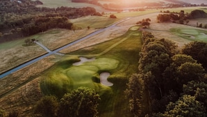 A golf course with a water hazard, sand bunkers, and a flagstick.