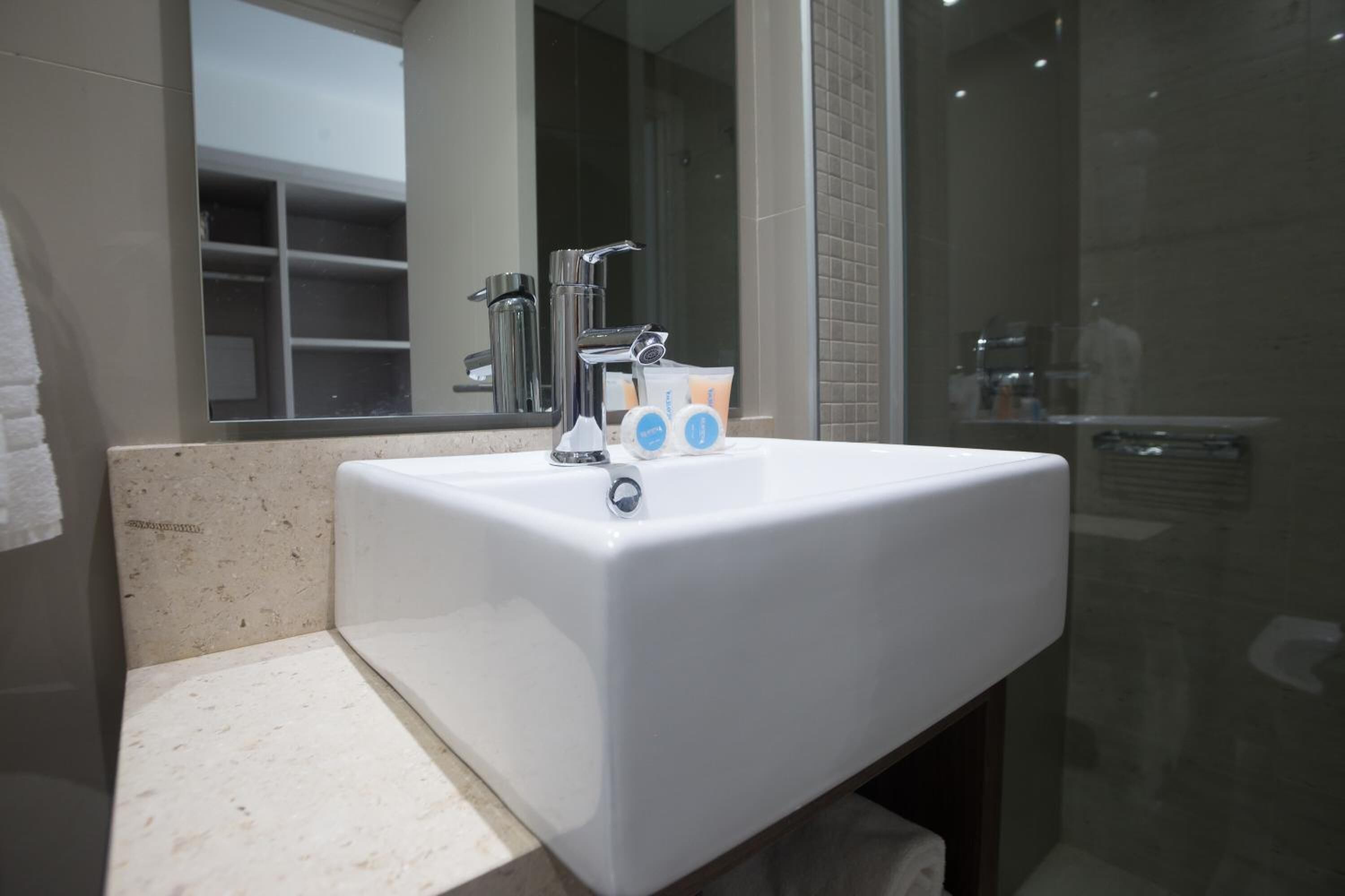 Un baño moderno con lavamanos blanco, grifo cromado y cabina de ducha de vidrio.