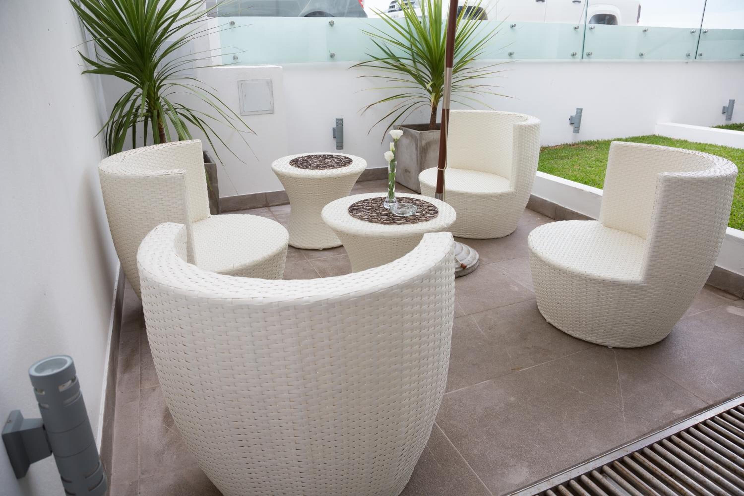 A modern outdoor seating area with wicker furniture and potted plants.