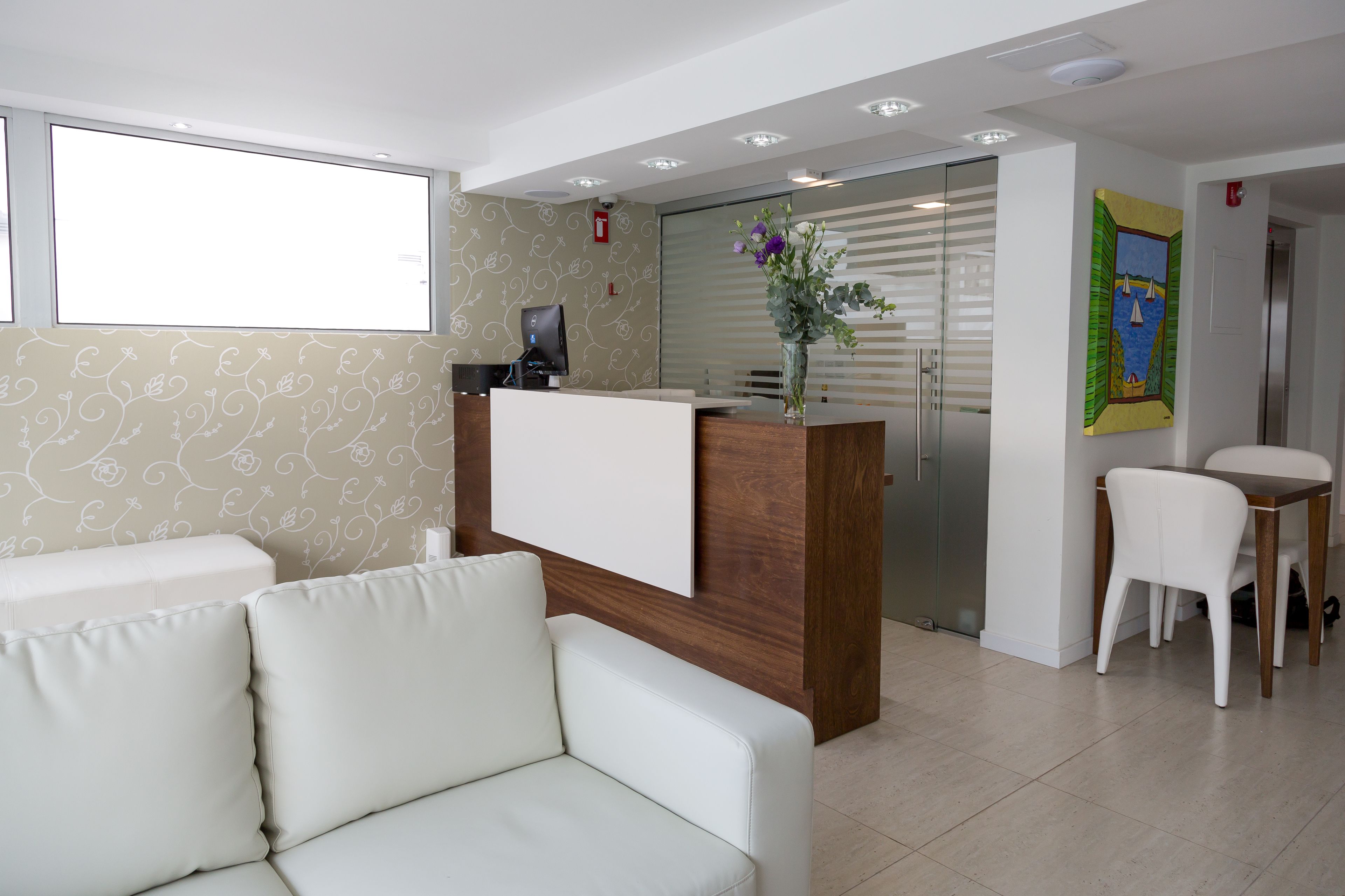 A reception area with a white sofa, a wooden reception desk, and a glass partition.
