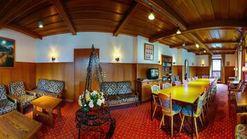 A cozy, wood-paneled room with a dining area, seating, and a television.