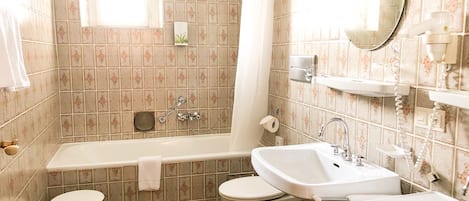 A bathroom with a bathtub, toilet, and two sinks.