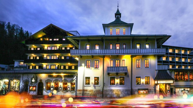 Un hôtel historique à étages, doté d’une tour imposante et de fenêtres illuminées.