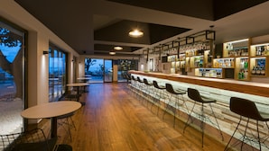 Un área de bar moderna con suelo de madera, taburetes y una variedad de botellas de licor.