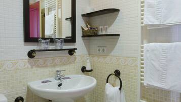 A bathroom with a white sink, a mirror, a towel rack, and a shelf with toiletries.