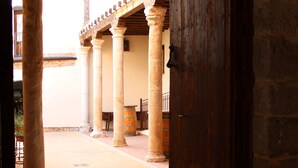 An open doorway leading to a courtyard with stone columns and a wooden door. - Palacio Rejadorada (Toro)