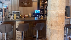 A bar area with a stone pillar, bar stools, a counter with a computer, and a sign reading "TONADA". - Palacio Rejadorada (Toro)