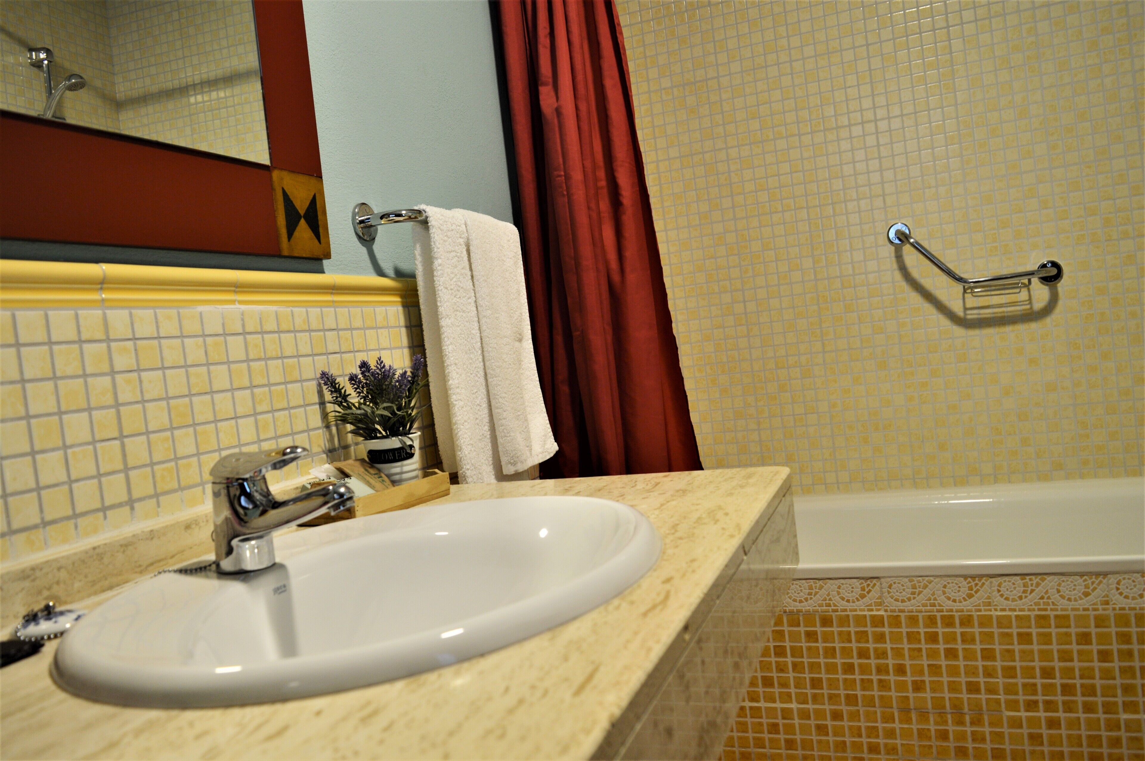 A bathroom with a sink, mirror, and bathtub.