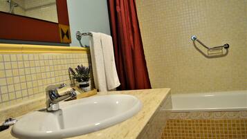 A bathroom with a sink, mirror, and bathtub.