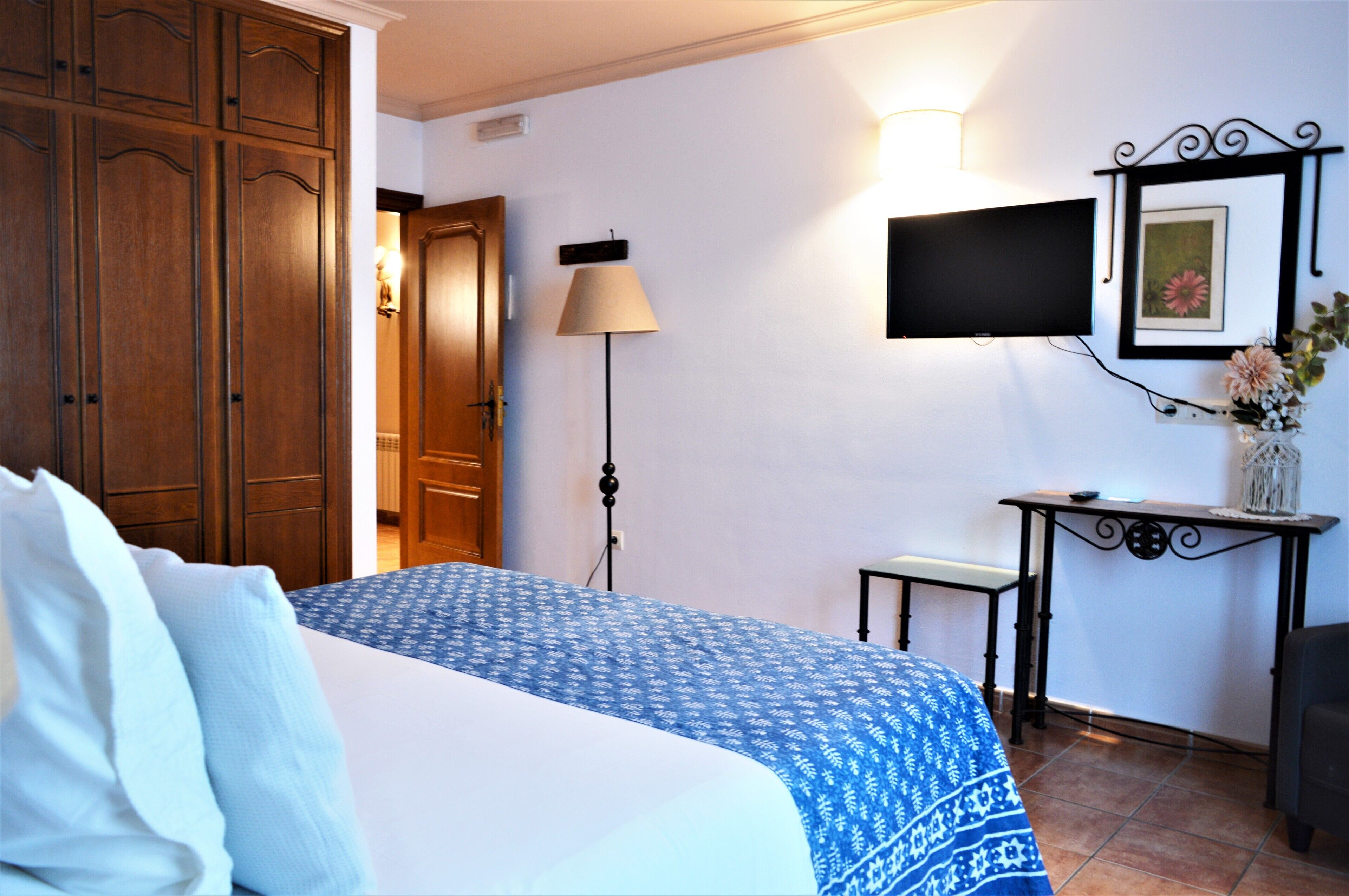 Una habitación de hotel con cama, escritorio, televisor y lámpara.