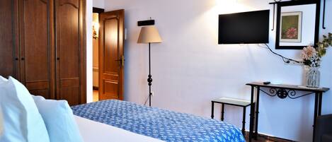 Una habitación de hotel con cama, escritorio, televisor y lámpara.