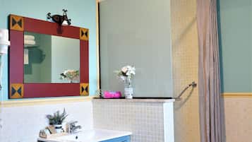 A bathroom with a sink, mirror, and shower.