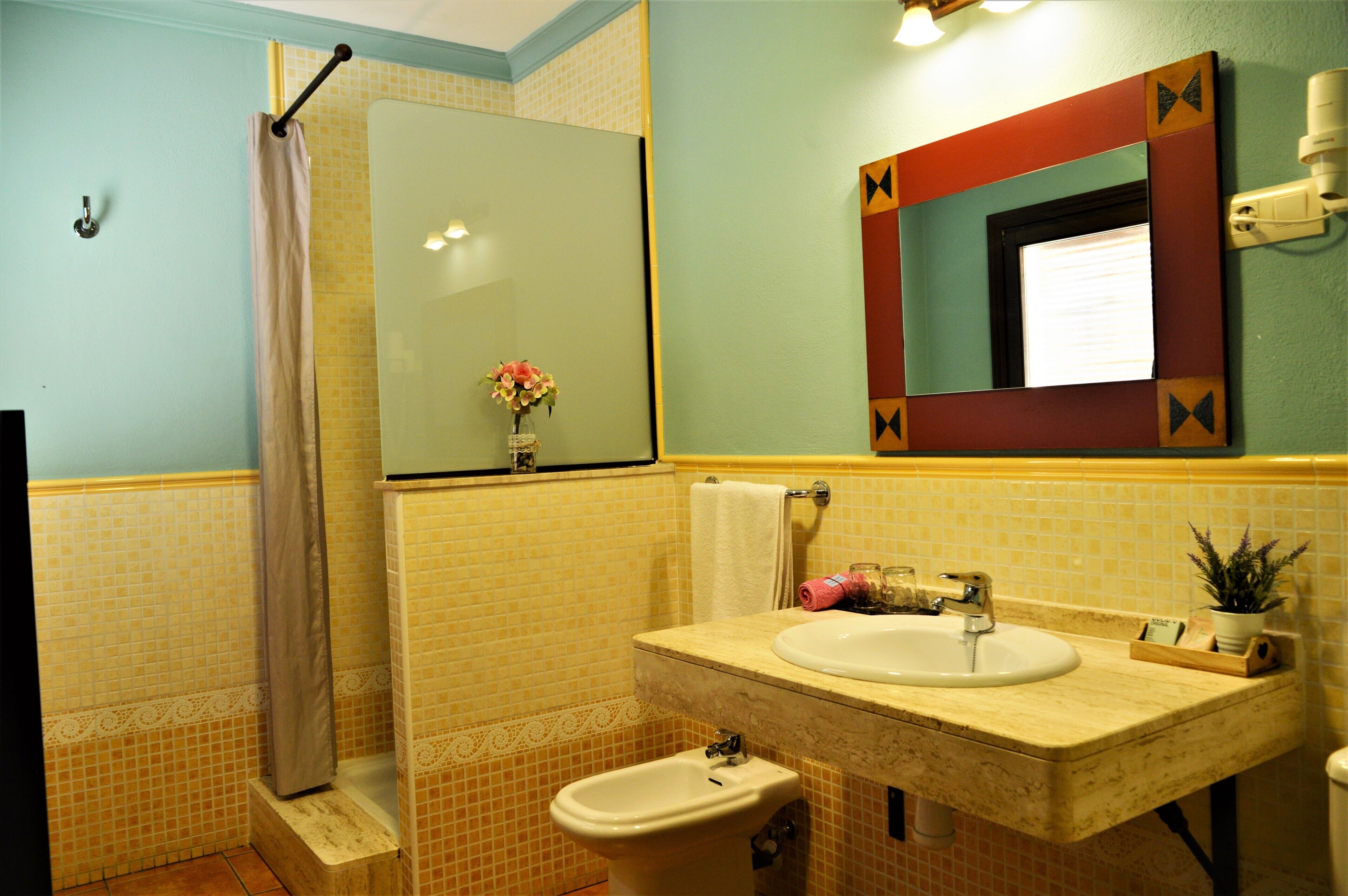 Ein Badezimmer mit Dusche, Bidet, Waschbecken und Spiegel.
