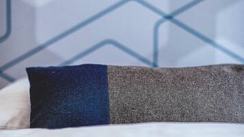 Una cama con un almohadón en tonos azul y gris.