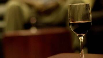 Ein Glas roter Wein auf einem braunen Ledersessel.