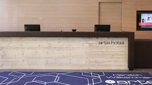 A reception desk with the name 'arte hotel' at the top. There are two black chairs in front of the desk. - arte Hotel Kufstein (Kufstein)