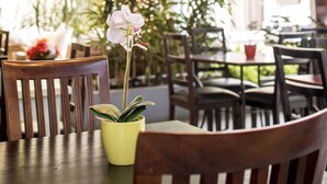 Ein Essbereich mit Holzkstühlen, einem gelben Tisch und einer Orchidee im Topf.