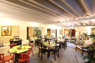 Un restaurante con varias mesas y sillas, algunas decoradas con plantas.