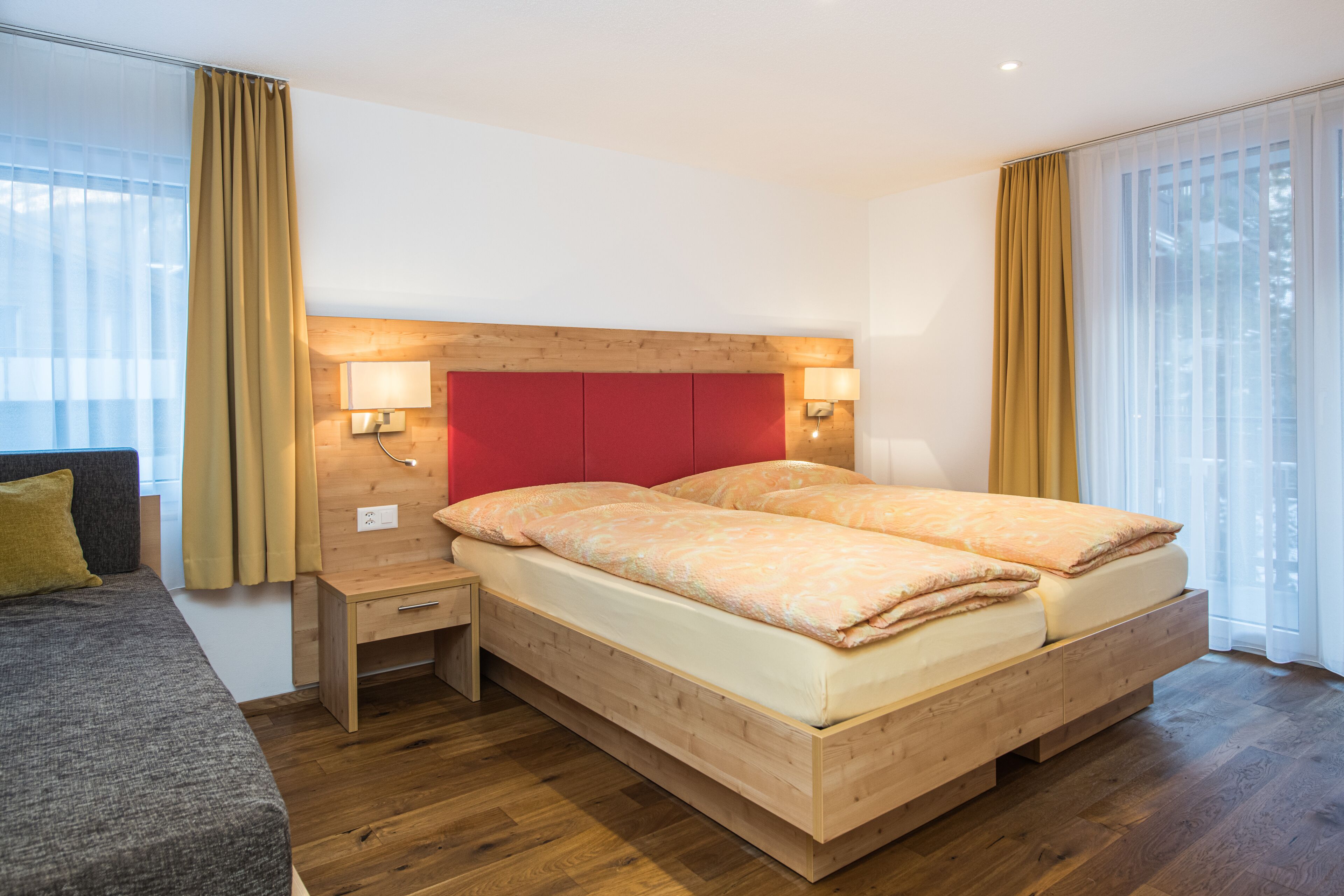 A modern hotel room with a wooden bed, bedside tables, and a view of the outdoors.