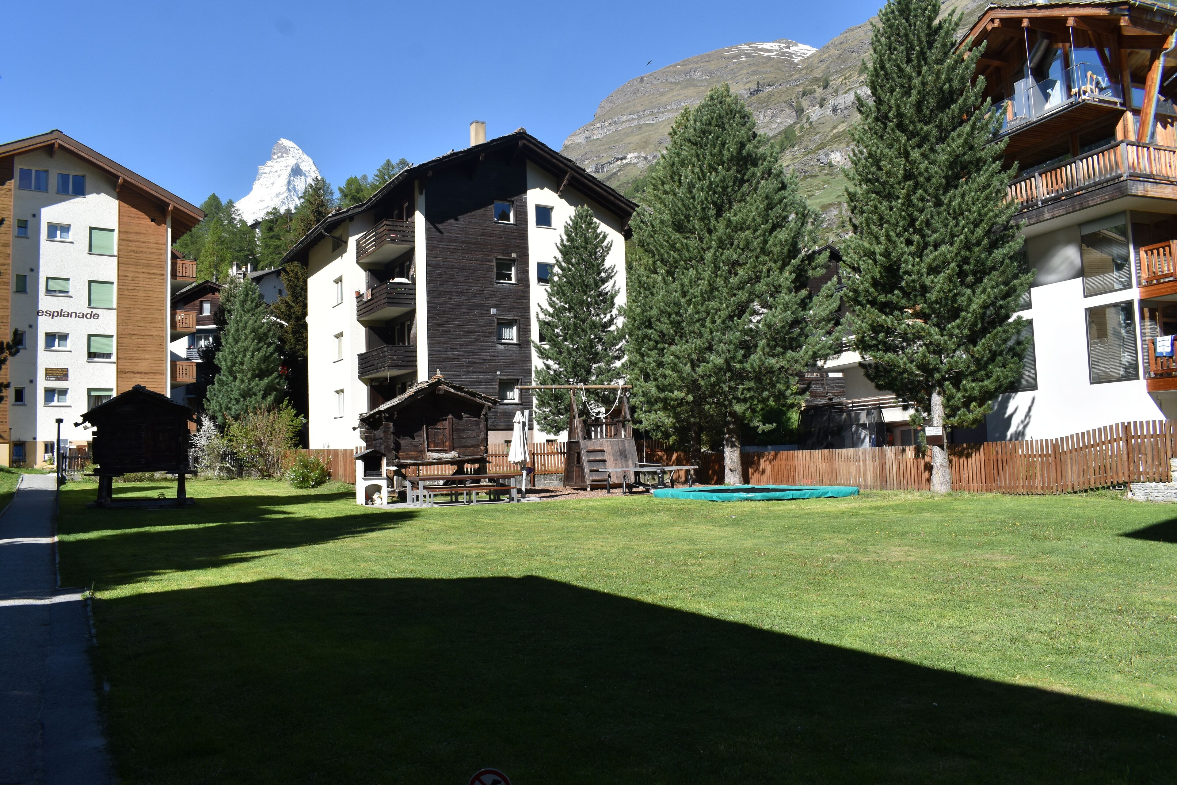 A hotel with multiple floors, outdoor seating, and a mountain backdrop.