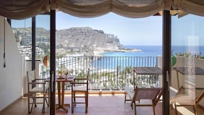 Un balcon offrant une vue sur un paysage côtier, comprenant une plage et une montagne.