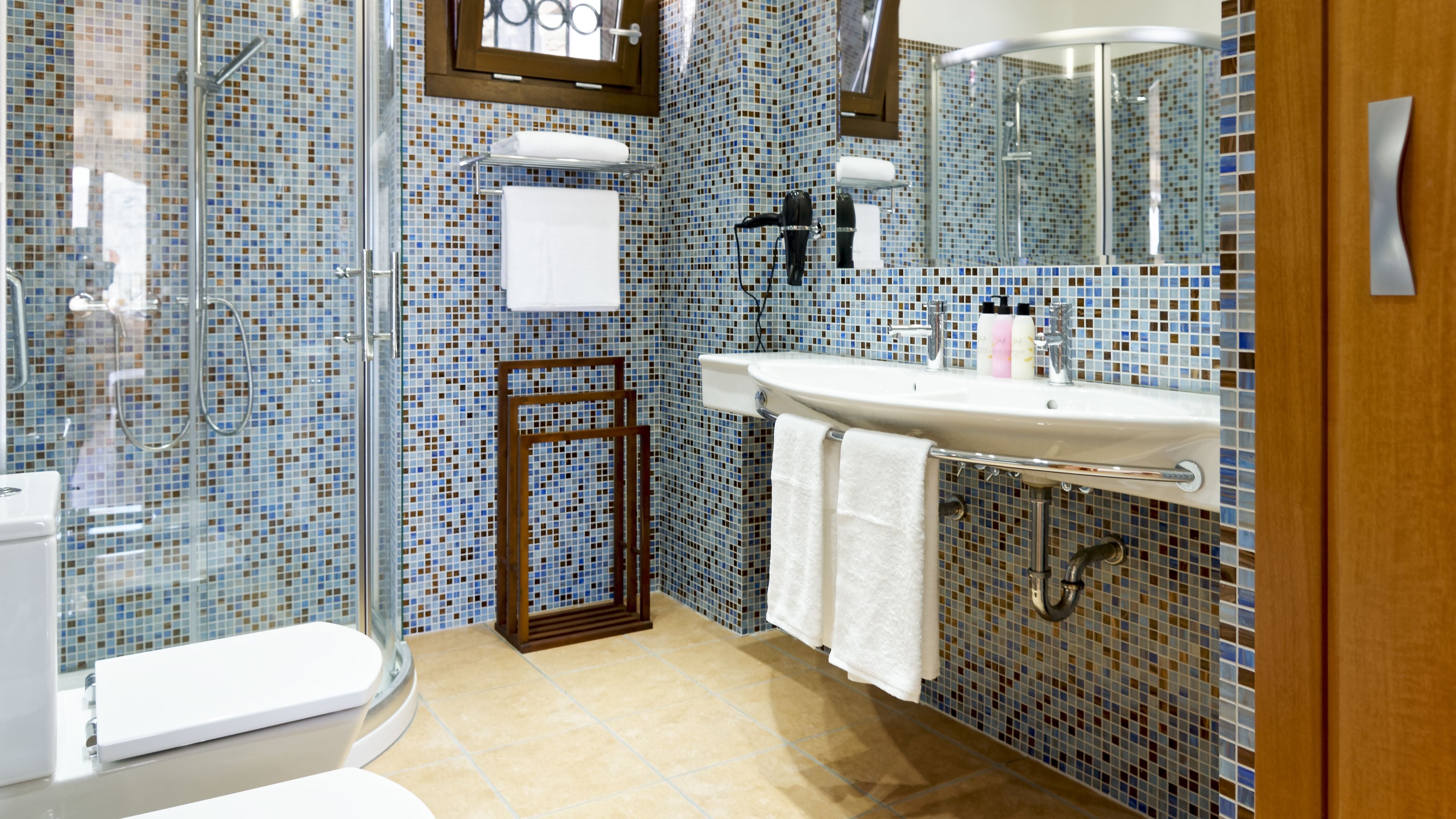 Un baño con cabina de ducha de vidrio, un lavamanos blanco con espejo y un inodoro.