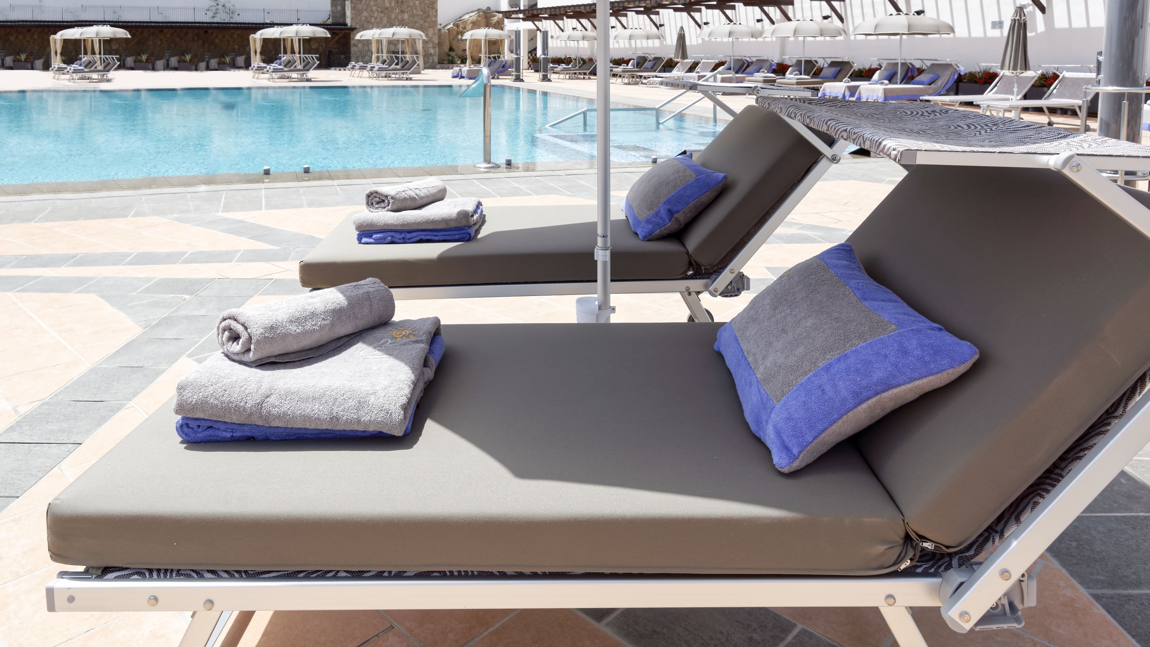 A poolside lounge area with sunbeds, towels, and umbrellas.
