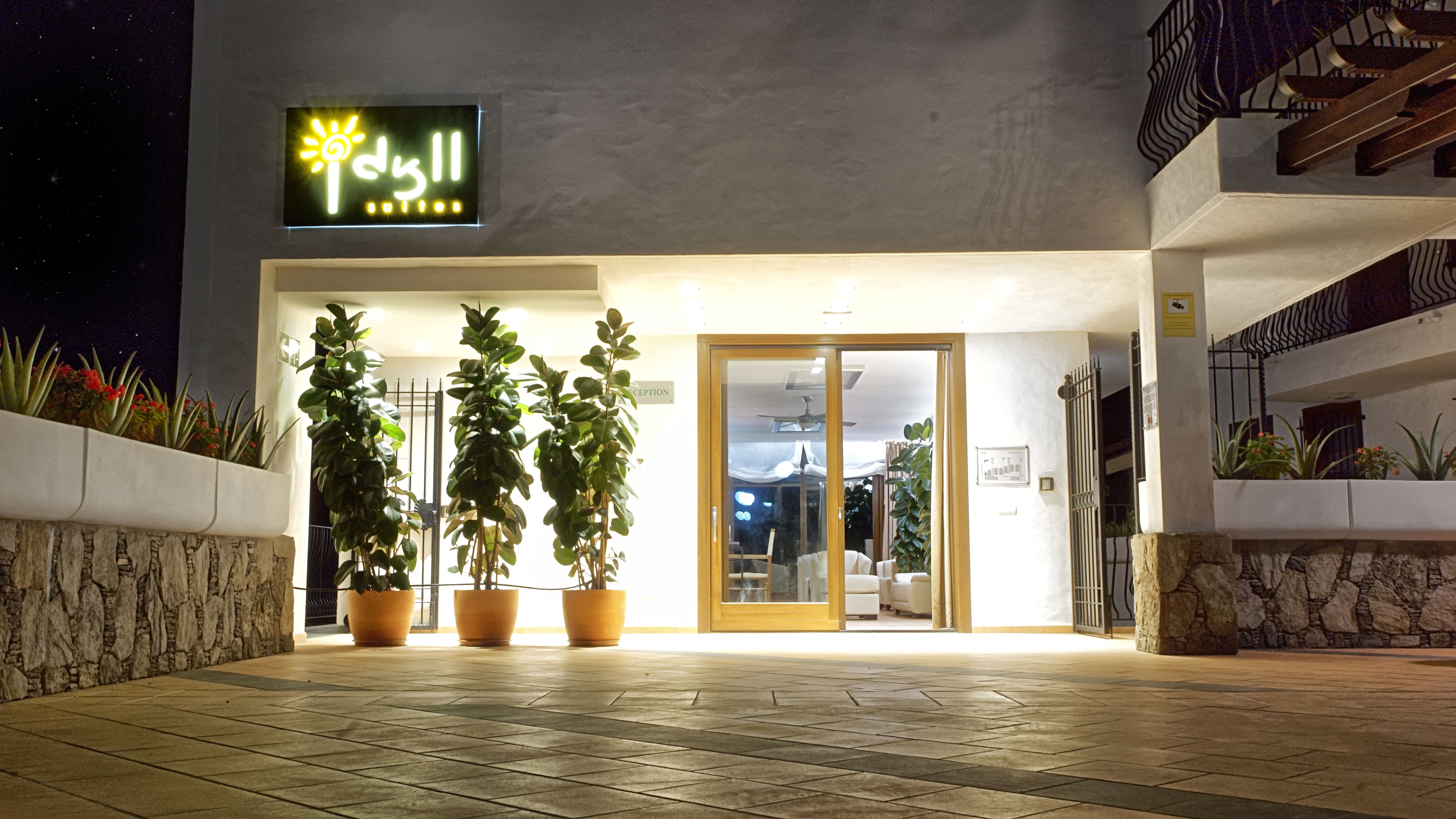 A modern building with a neon sign, potted plants, and a reception area.
