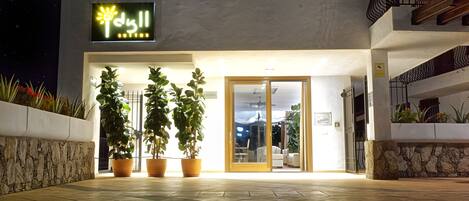 A modern building with a neon sign, potted plants, and a reception area.