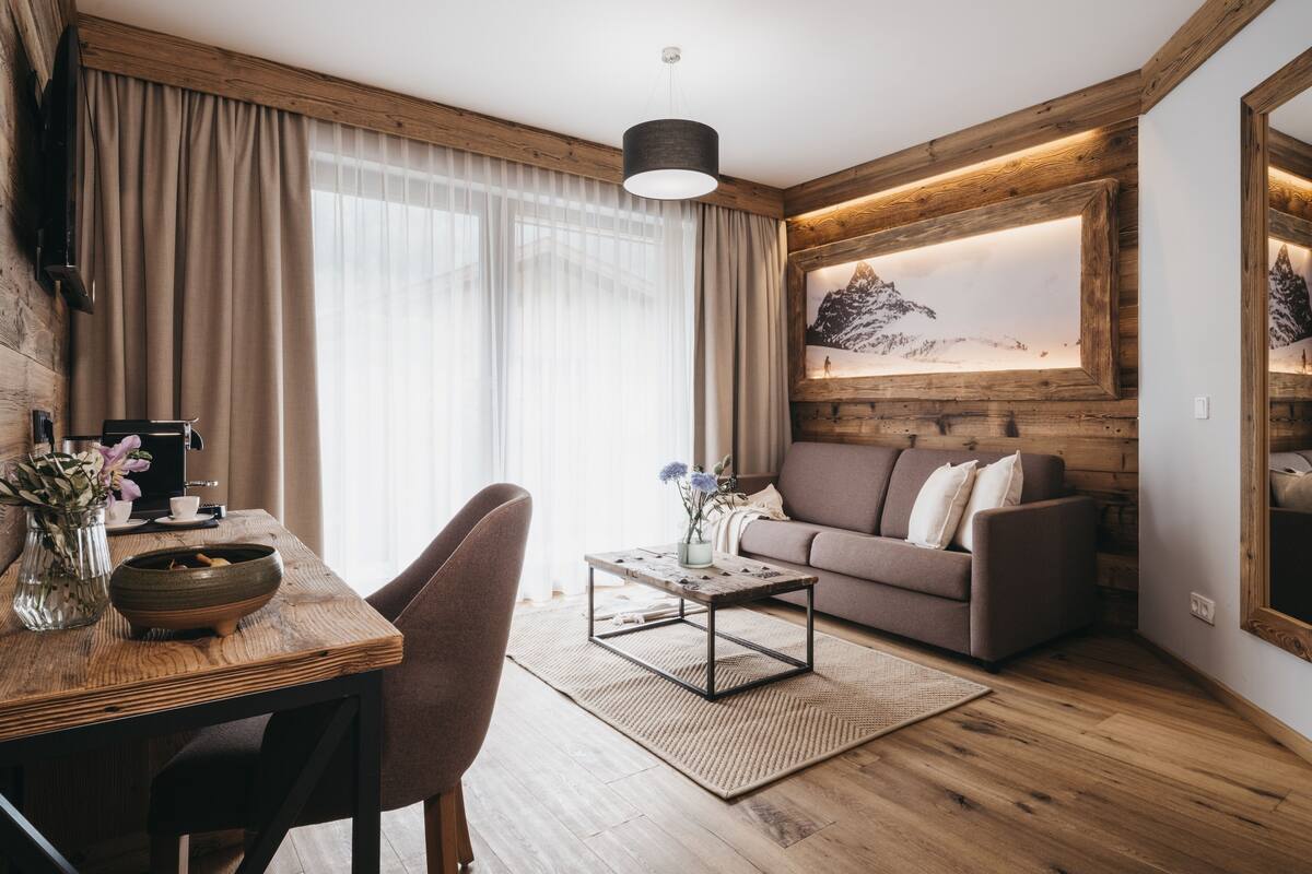 Una sala de estar acogedora con piso de madera, un sofá, una mesa de centro y un comedor con mesa y sillas.