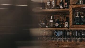 A bar area with shelves of liquor bottles and a row of glasses.